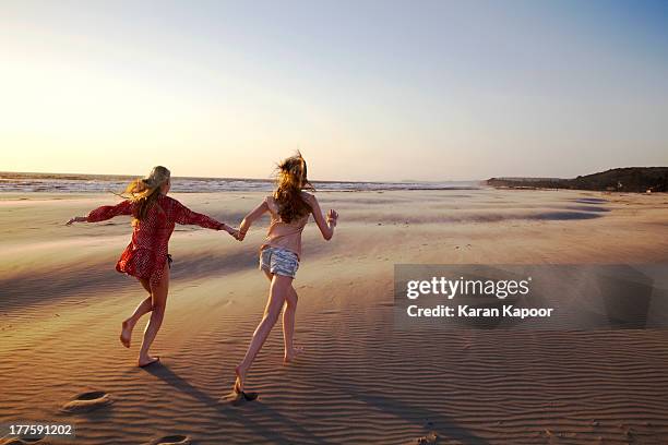 maother and daughter running on empty beach - cheveux au vent photos et images de collection