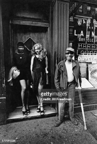 Two women in a doorway and a homeless man pose for a photograph, New York City, circa 1978.