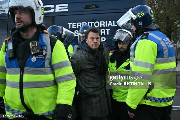 Police officers arrest a man, part of a group of counter-protesters, close to the 'National March For Palestine' in central London on November 11 as...