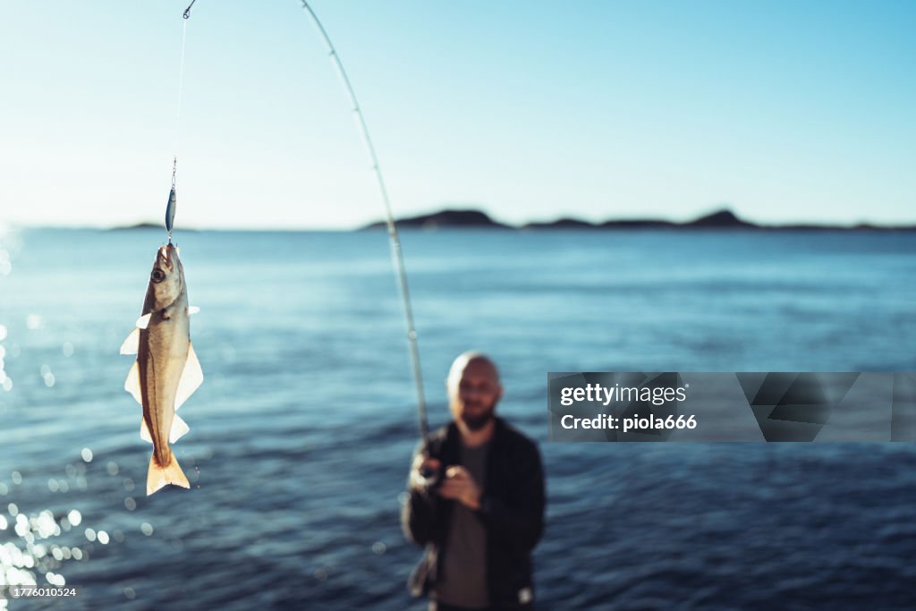 Homme tournant la pêche dans la mer avec une tige, des roches