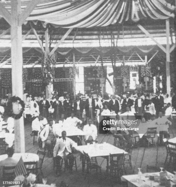 View of the great sanitary fair, showing an interior view of a large banquet hall with African American men standing and sitting at the tables,...