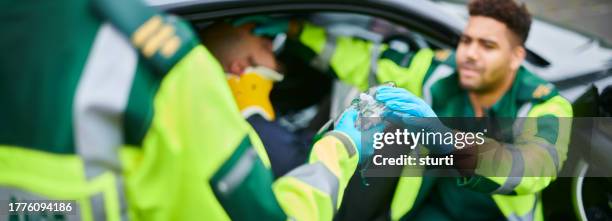 paramedics administering oxygen at car crash - casualty stock pictures, royalty-free photos & images