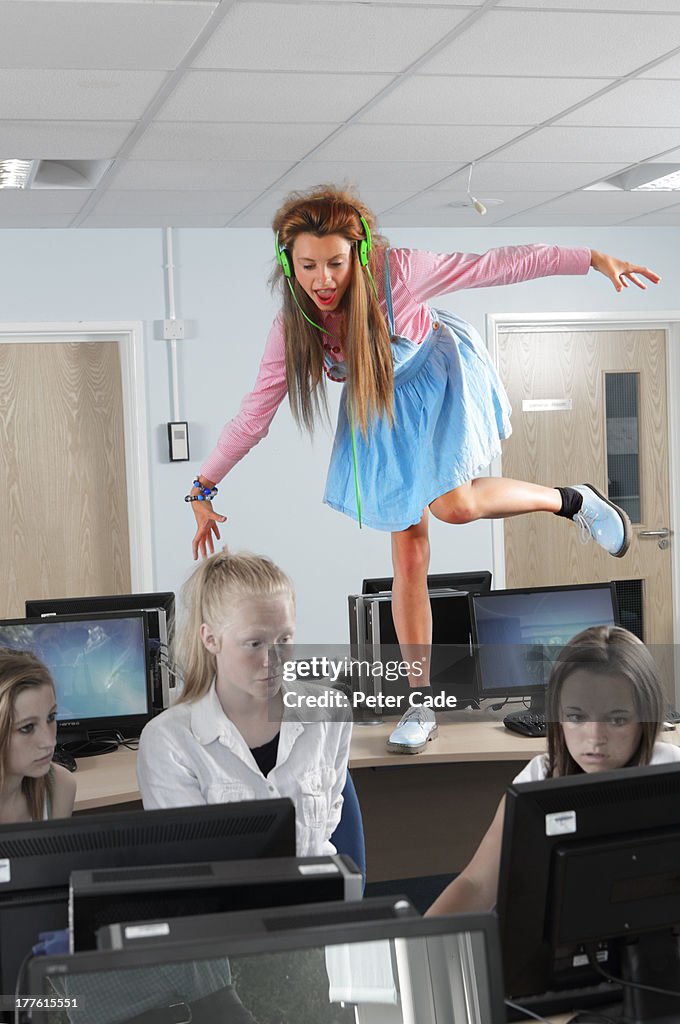 Girl stood on desk showing off in classroom