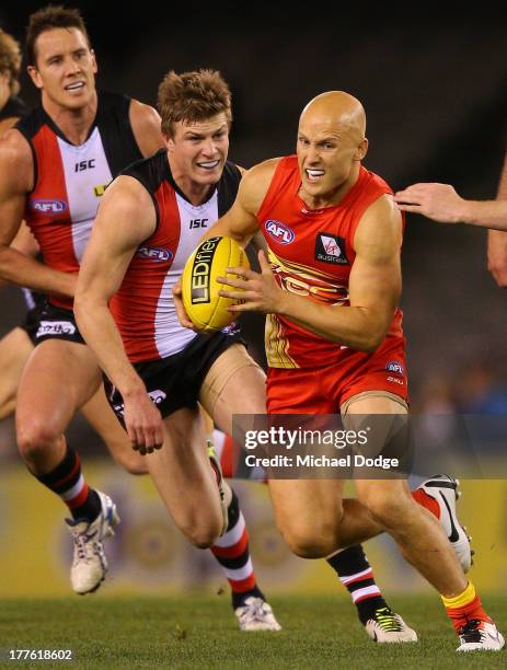Gary Ablett of the Suns runs with the ball away from Jack Newnes of the Saints during the round 22 AFL match between the St Kilda Saints and the Gold...