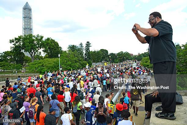 Kyev Tatum of Ft. Worth, TX photographs marchers on the Kutz Bridge during the 50th Anniversary of March On Washington in Washington, DC on August...