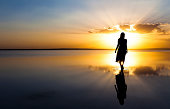 Young woman walking on water at sunset