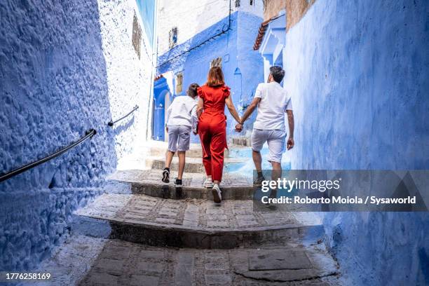 family with one boy exploring the blue city of chefchaouen - morocco stock pictures, royalty-free photos & images