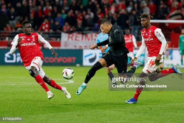 Kylian Mbappe of Paris Saint-Germain controls the ball against Joseph Stanley Okumu of Stade de Reims and Emmanuel Agbadou of Stade de Reims during...