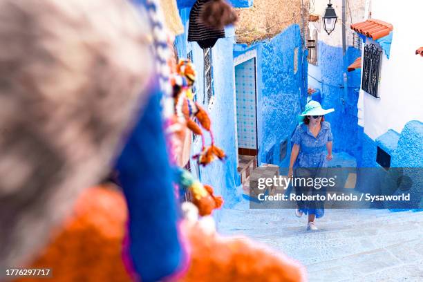 cheerful woman walking on blue steps of medina - chefchaouen medina stock pictures, royalty-free photos & images