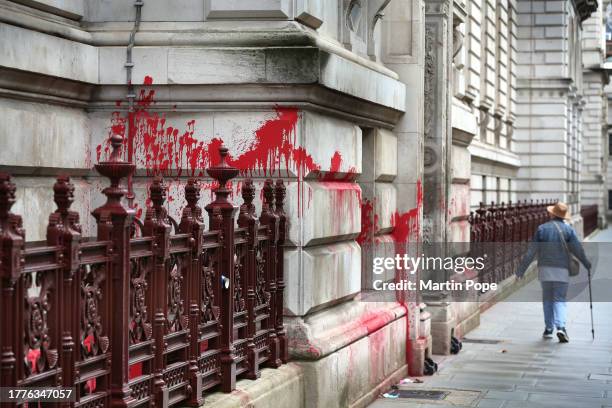 Passer-by walks beside the Foreign Office, an attempted clean up of graffiti has left the stones scarred and with a pink tinge on November 4, 2023 in...