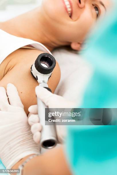 woman smiling laying while getting a dermoscopy on arm - melanoma stock pictures, royalty-free photos & images