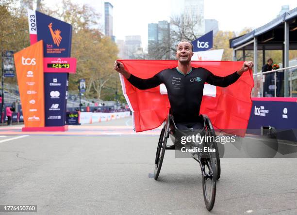 Marcel Hug of Switzerland poses with the flag after he crossed the finish line to win the Men's Wheelchair division during the 2023 TCS New York City...