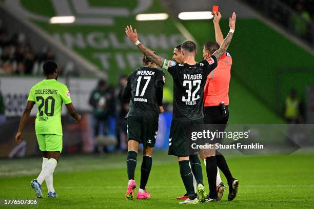 Referee Tobias Reichel shows a red card to Maxence Lacroix of VfL Wolfsburg following a second yellow card during the Bundesliga match between VfL...