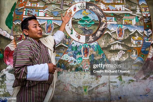 guide with mural at trongsa dzong - museum guide stock pictures, royalty-free photos & images