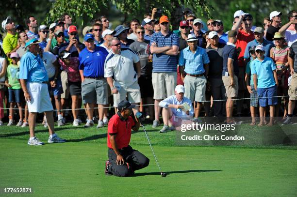 Tiger Woods falls to the ground in pain after hitting his second shot on the 13th hole during the final round of The Barclays at Liberty National...