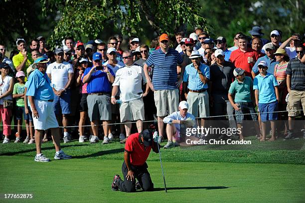 Tiger Woods falls to the ground in pain after hitting his second shot on the 13th hole during the final round of The Barclays at Liberty National...