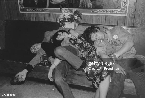 Three drinkers at an Irish bar, one wearing a 'Victory To The IRA' badge, sleep on top of each other at closing time, New York City, circa 1978.