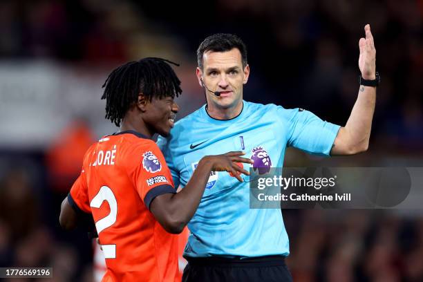 Referee Andrew Madley gestures for Issa Kabore of Luton Town to receive medical treatment to a facial injury during the Premier League match between...