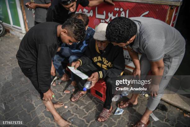 Palestinians read the leaflets that Israeli Army dropped, demanding urgent information on Israeli hostages and Hamas, in Khan Yunis, Gaza on November...