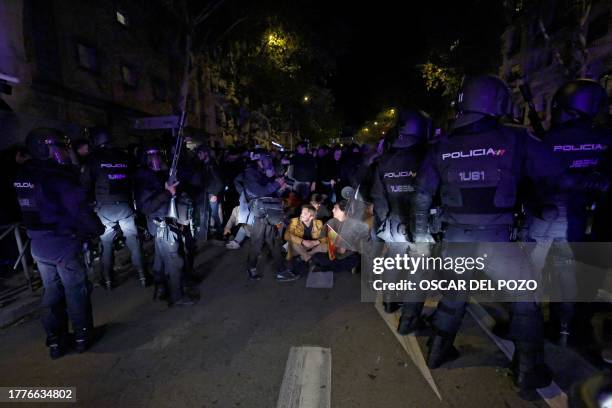 Demonstrators sit on the pavement in front of members of the police forces during a protest called by far-right and right-wing movements against...