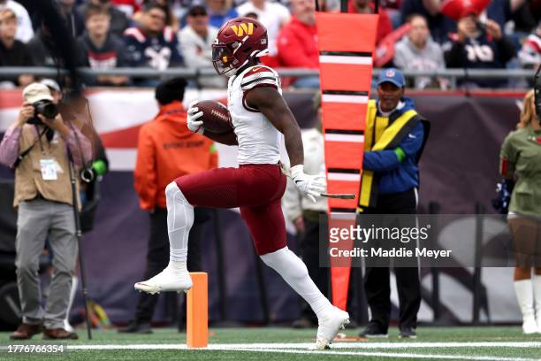 Brian Robinson Jr. #8 of the Washington Commanders carries the ball for a touchdown against the New England Patriots during the second quarter of the...