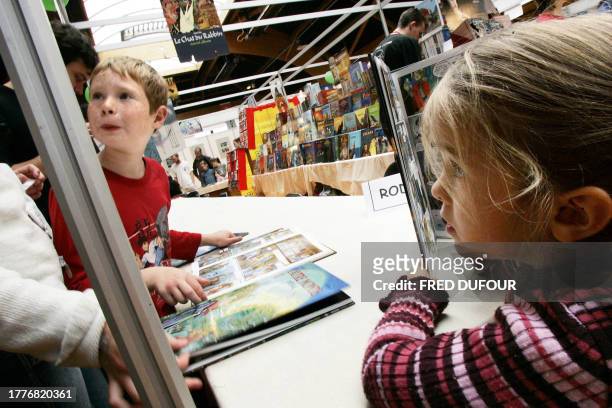 Des enfants feuilletent des livres, le 28 octobre 2005, sur un des stands du 25e Festival de la bande dessinée "Quai des bulles" de Saint-Malo. Pour...