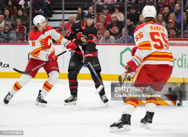 Mathieu Joseph of the Ottawa Senators deflects the puck past Dustin Wolf of the Calgary Flames as Chris Tanev and Noah Hanifin of the Calgary Flames...