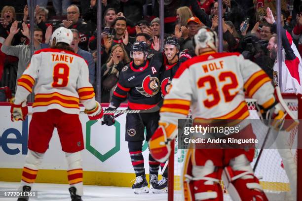 Mathieu Joseph of the Ottawa Senators celebrates his first period goal against the Calgary Flames with teammate Claude Giroux as Chris Tanev and...