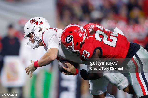 Jaxson Dart of the Mississippi Rebels is tackled by Tykee Smith of the Georgia Bulldogs during the first half at Sanford Stadium on November 11, 2023...