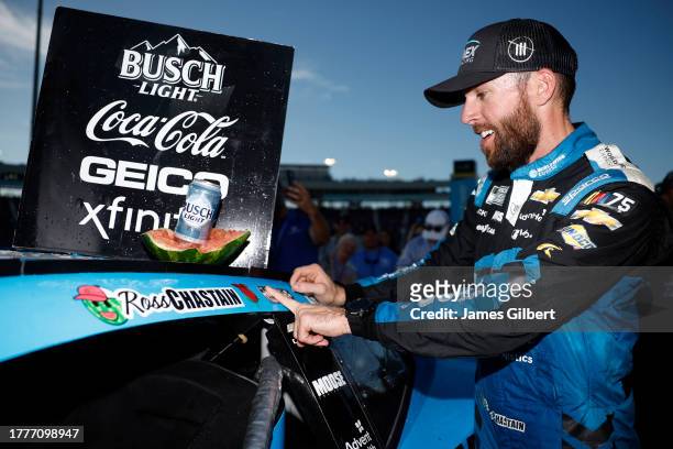 Ross Chastain, driver of the Worldwide Express Chevrolet, places the winner sticker on his car in victory lane after winning the NASCAR Cup Series...