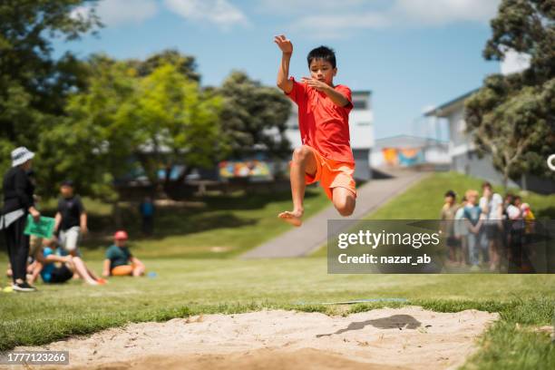 kid taking part in long jump in a school competition. - salto em comprimento imagens e fotografias de stock
