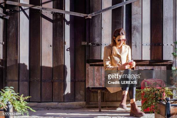 female tourist sitting on a bench in the narrow streets of a european city - lerexis stockfoto's en -beelden
