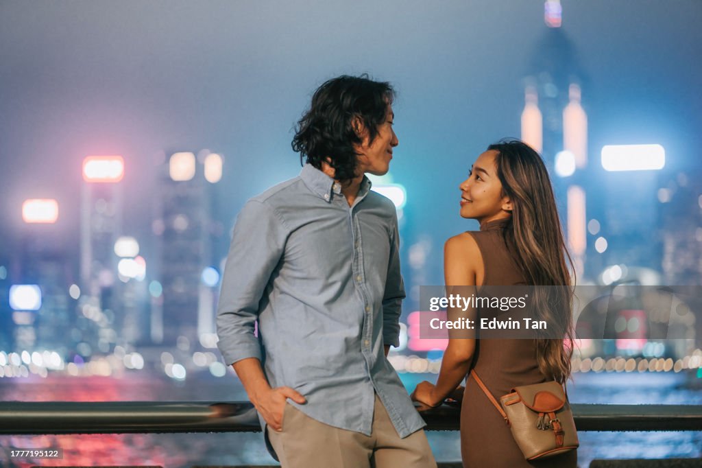 Turista asiático chino de la pareja que mira el paisaje urbano de Hong Kong por la noche desde la avenida de la estrella de kowloon