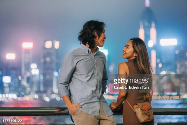 asian chinese couple tourist looking at hong kong cityscape at night from kowloon star avenue - tsim sha tsui stock pictures, royalty-free photos & images