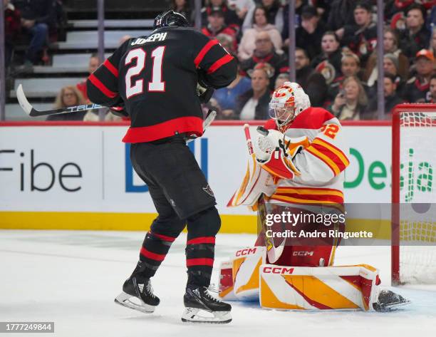 Dustin Wolf the Calgary Flames tries to control the puck with Mathieu Joseph of the Ottawa Senators looking for a rebound during the third period at...