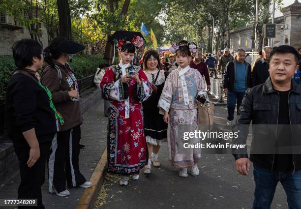 Chinese tourists, some dressed in traditional Hanfu clothing, walk near the Shichahai Lake and Houhai Lake areas on November 3, 2023 in Beijing,...