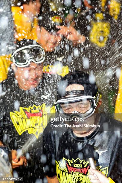 Head coach Akinobu Okada of Hanshin Tigers is poured beers as the team celebrates winning the Japan champions following the team's 7-1 victory in the...