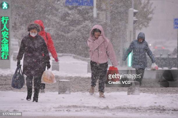 People walk along a road during a snowstorm on November 6, 2023 in Harbin, Heilongjiang Province of China.
