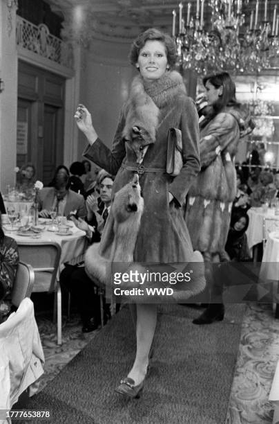 Model Marion York poses in a double fox trimmed fur coat, logo clutch bag, and horsebit loafer from Gucci's fall 1973 collection.