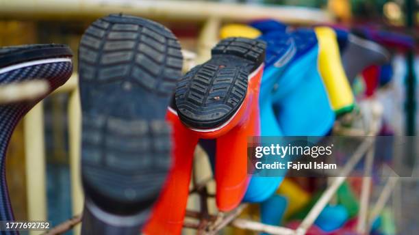 colorful rubber boots hanging from a fence - rubber boots stock-fotos und bilder