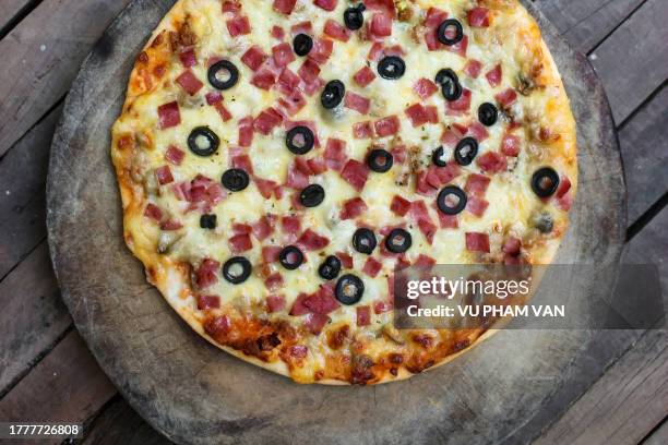 pizza with ham and olives on wooden table - pizza temptation stock pictures, royalty-free photos & images