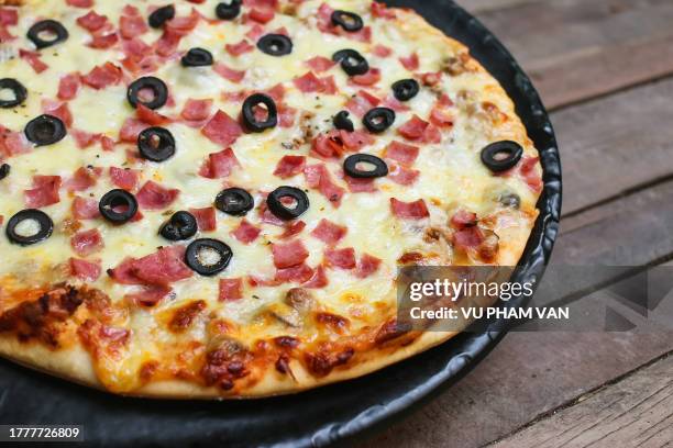 pizza with ham and olives on wooden table - oliva nera foto e immagini stock
