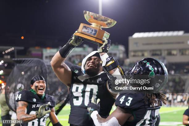 John Tuitupou of the Hawaii Rainbow Warriors hoists the General Laurence S. Kuter Trophy after winning the game against the Air Force Falcons at the...