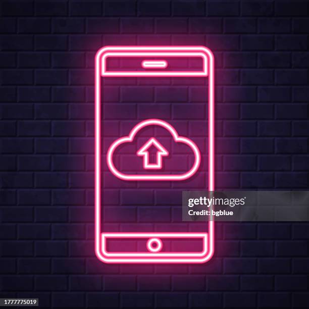cloud upload from smartphone. glowing neon icon on brick wall background - touch screen wall stock illustrations