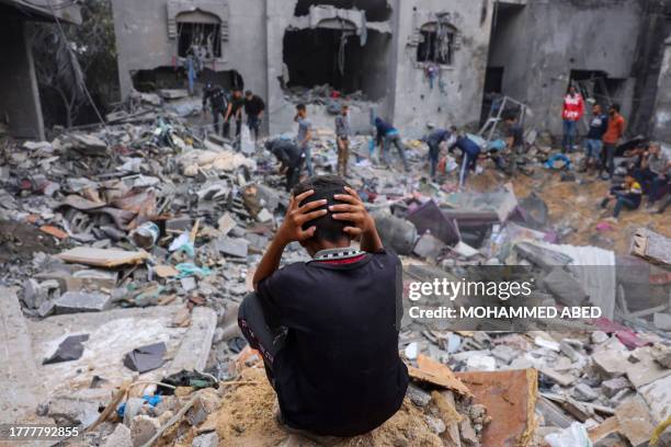 Child reacts as people salvage belongings amid the rubble of a damaged building following strikes on Rafah in the southern Gaza Strip, on November 12...