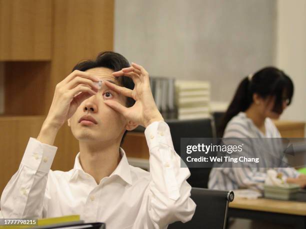an asian man felt uncomfortable in his eyes after working for too long and was about to take some eye drops. - eye drop stock pictures, royalty-free photos & images