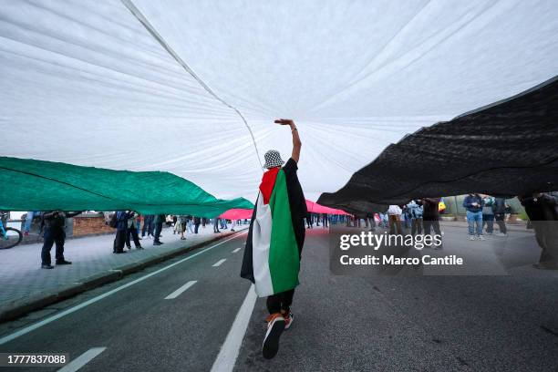 Man under a giant flag, during the demonstration in Naples in solidarity with the Palestinian people after Israel's attacks on the Gaza strip, near...