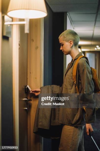 side view of non-binary business person entering hotel room using keycard - keycard access stock pictures, royalty-free photos & images