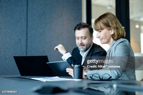 a good risk management strategy can help protect your brand. senior businesswomen in executive meetings show business vision on a tablet computer with businessmen in a meeting room. - finansiell rådgivare bildbanksfoton och bilder