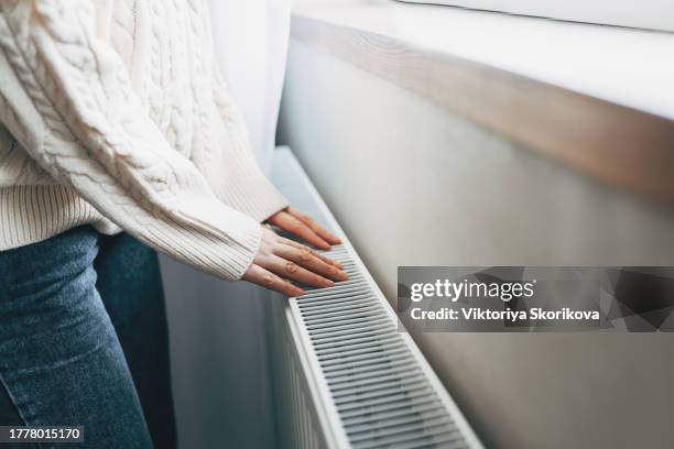 central heating problem at home. woman checking heating radiator in cold apartment - heizung stock-fotos und bilder
